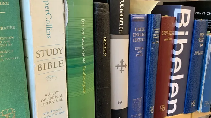 bokhylle med diverse utgaver av novum testamente graece og norske oversettelser av Bibelen